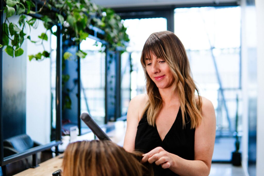 Hairstylist applying hair extensions at Iron + Ivy Queenstown